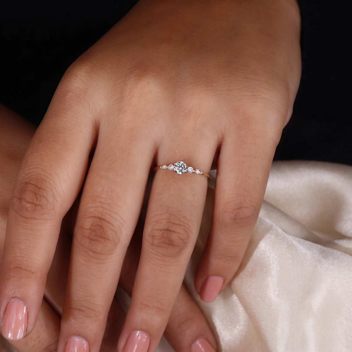 round cut diamond engagement ring with graduated side stones and petal gallery